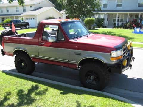 1995 Ford Bronco - This two-tone red and silver Ford Bronco is parked curbside on a sunny day.