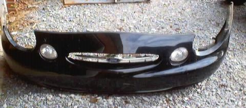 1999 Ford Taurus - A black front bumper assembly, likely from a 1998 vehicle, is displayed against a gravel background.