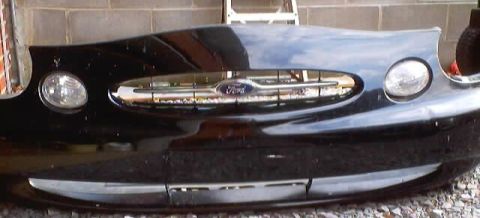 1999 Ford Taurus - Front bumper assembly for a 1999 Ford Taurus, the distinctive grille and headlight housings.