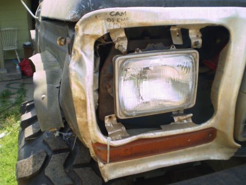 1978 Ford Bronco - The front of a damaged vehicle shows a large headlight and an orange turn signal, with 'CAM OPEN' scrawled on the fender.
