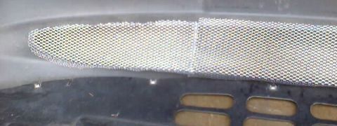 1999 Ford Taurus - A close-up view of a vehicle's mesh grille, with a SuperMotors logo visible.