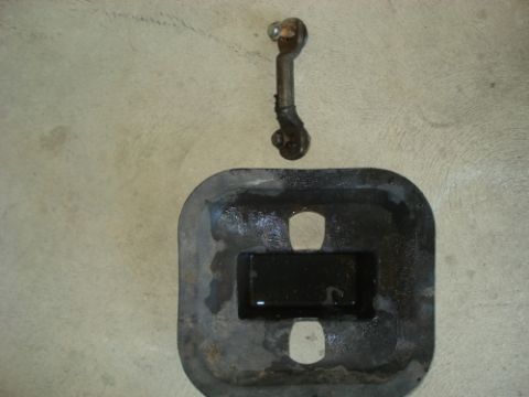 1990 Ford Bronco - Two automotive parts, a metal linkage and a rubber gasket, are displayed against a concrete background.