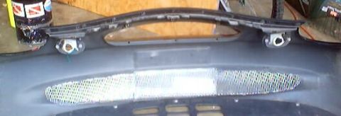 1999 Ford Taurus - A car bumper part with a mesh grille is shown, with no visible year identification.