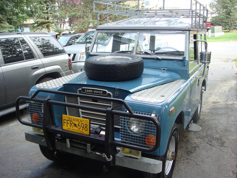 Blue Land Rover Series with brush guard, roof rack and hood-mounted spare