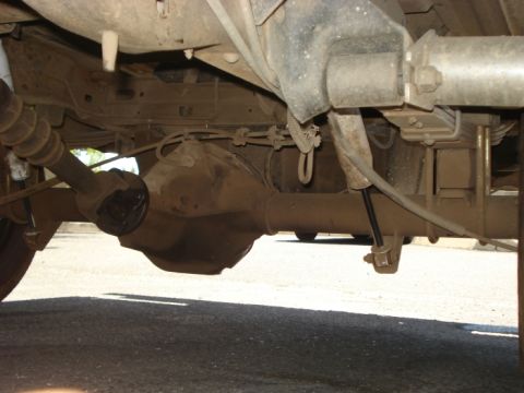 1990 Ford Bronco - The underside of a vehicle shows the rear differential, driveshaft, and suspension components.