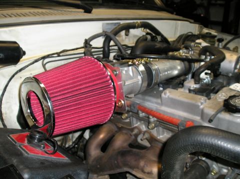 1986 Toyota Hilux - Close-up of an engine bay an aftermarket air intake system and various hoses.