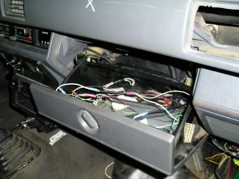 1986 Toyota Hilux - The open glove box reveals a mess of wires and electrical connections within the vehicle's dashboard.