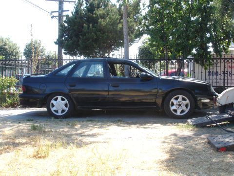1991 Ford Taurus - Side profile of a black 1991 Ford Taurus sedan parked outdoors.