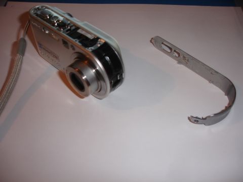 1993 Ford Taurus - A silver digital camera lies disassembled next to its broken metal strap bracket.