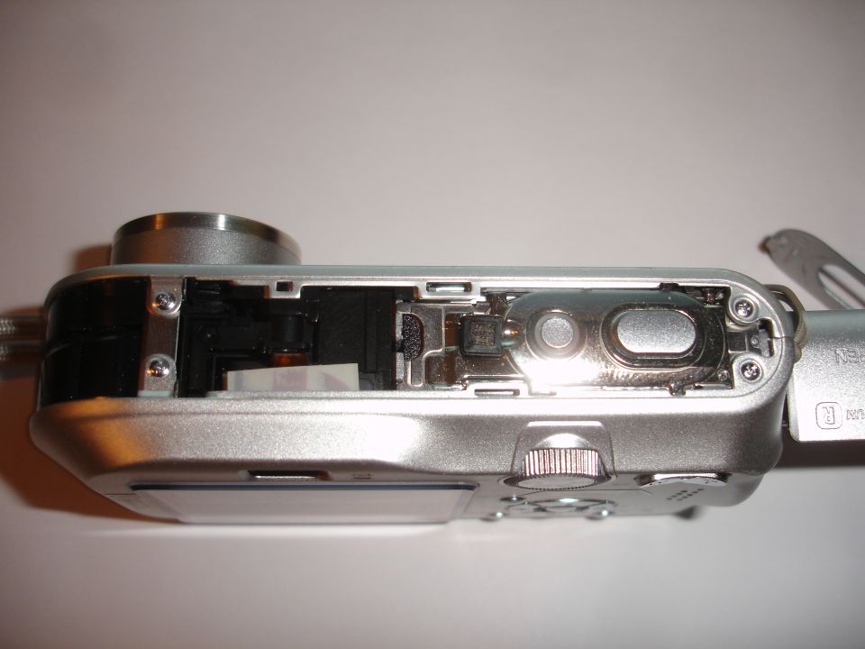 digital camera with side panel removed showing internal components like circuit board and lens mechanism