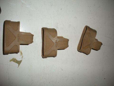 1996 Ford Bronco - Three tan plastic parts are laid out on a white surface, showing their textured surfaces and some imprinted text.
