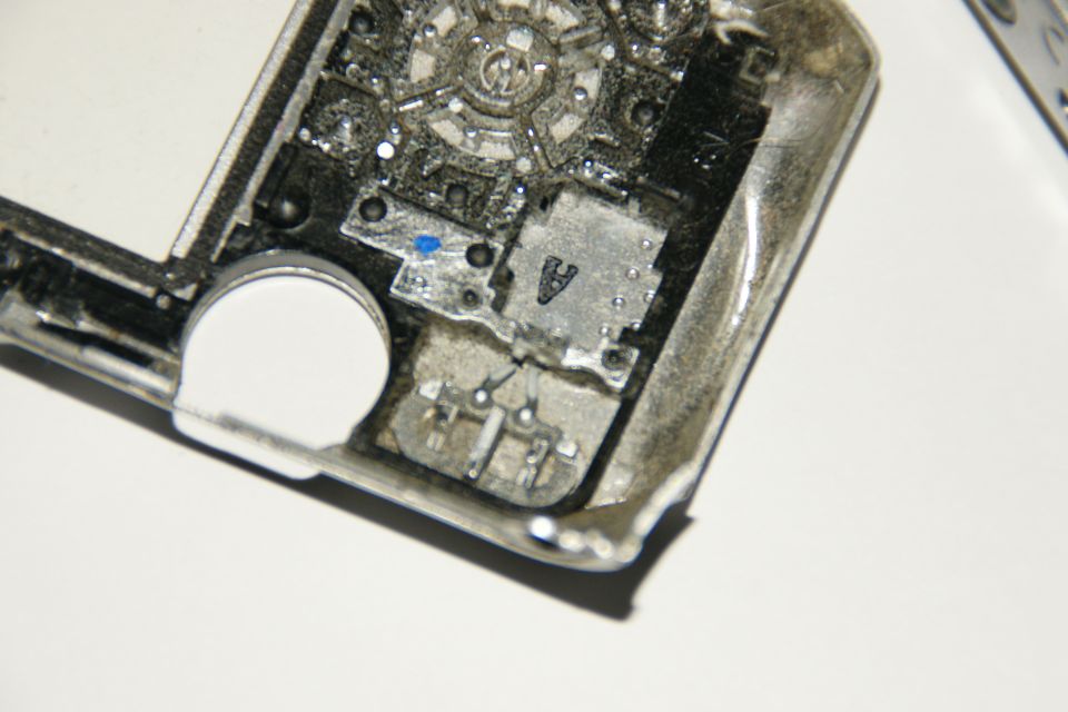 Inside of a car key fob showing circuit board, battery, and metal contacts