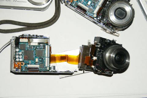 1993 Ford Taurus - A digital camera is disassembled, revealing its internal circuit boards and lens mechanism.