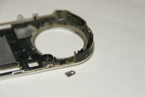 1993 Ford Taurus - A disassembled camera body and a small metal bracket lie on a white surface.