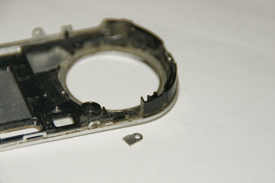 Disassembled camera body with a small metal bracket nearby