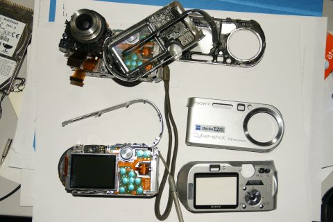 1993 Ford Taurus - Several disassembled Sony Cyber-shot digital cameras and a hard drive are laid out on a white surface.