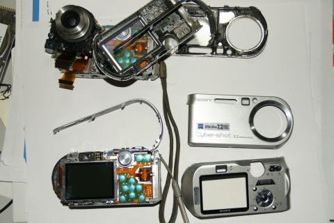 1993 Ford Taurus - Internal workings and exterior shells of two Sony Cyber-shot digital cameras are displayed on a flat surface.