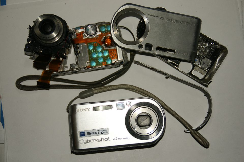 Sony Cyber-shot camera disassembled, showing internal components and a separate intact camera