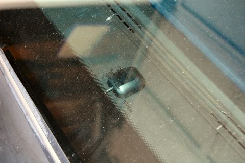 1985 Mercury Grand Marquis - Close-up of a car's windshield wiper motor, showing dust and markings on the glass.