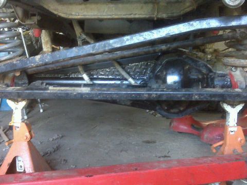 1992 Ford F-350 - Underbody view of a vehicle's rear axle and suspension system, supported by jack stands. Text from a watermark is visible at the bottom rig…