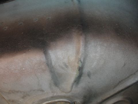 1991 Ford Taurus - The underside of a car's hood shows some minor damage and overspray from painting.