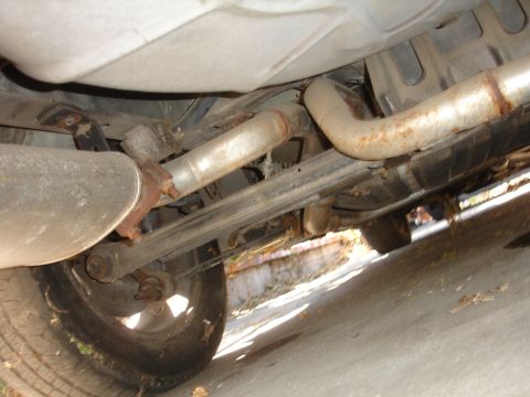 1991 Ford Taurus - Underside view of a car's exhaust system and rear suspension components, including the tire.
