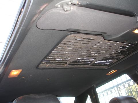 1991 Ford Taurus - The interior ceiling of a car shows a torn sunroof shade and illuminated lights.
