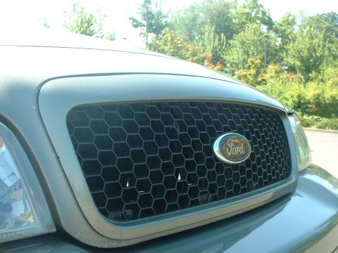 2000 Ford Crown Victoria - The front grille of a Ford Crown Victoria features a honeycomb pattern and the iconic Ford emblem.
