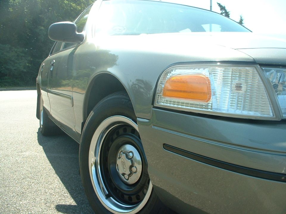Gray 2000 Ford Crown Victoria front quarter panel and wheel, with chrome trim and black steel wheel