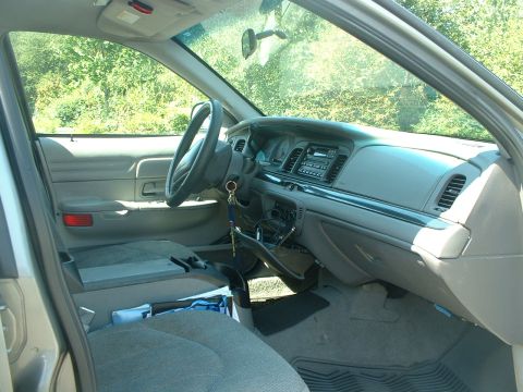 2000 Ford Crown Victoria - The interior of a car is shown, with a view of the dashboard, steering wheel, and seats.