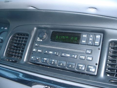 2000 Ford Crown Victoria - The dashboard of a car features a radio with a digital display showing the time and air vents on either side.