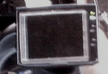 1999 Ford Taurus - blurry close-up of a small handheld device with a square LCD display and a few side buttons.