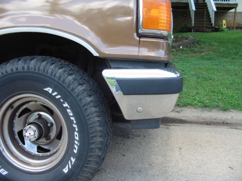 1988 Ford Bronco - Close-up of the front corner of a 1988 Ford Bronco, showing the tire and bumper.
