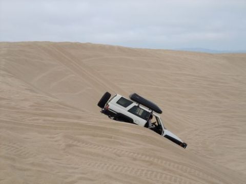 1985 Toyota 4Runner - A white SUV is stuck on a steep sand dune, with tire tracks visible on the slope.