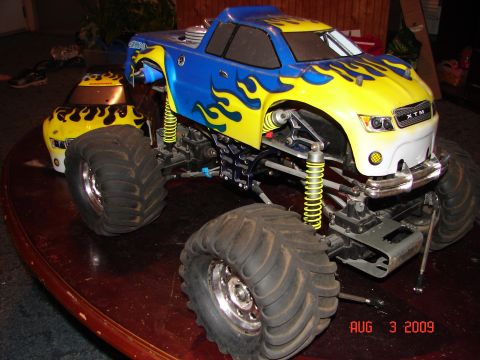 1987 Ford Bronco - RC monster truck with large tires and custom flame paint job sits on a table.