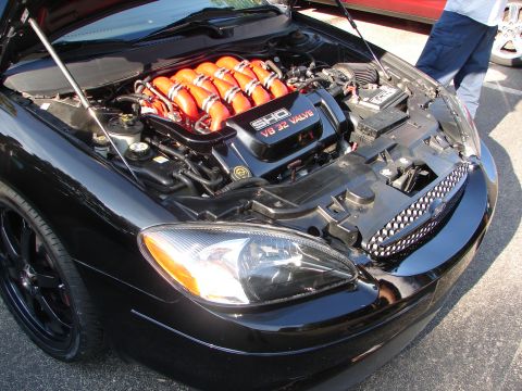 1992 Ford Taurus - Black Ford Taurus with its hood open, revealing the SHO V8 32 valve engine and custom intake runners.