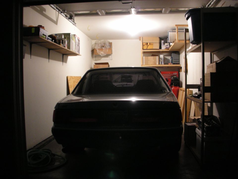 Rear view of a dark sedan parked in a garage