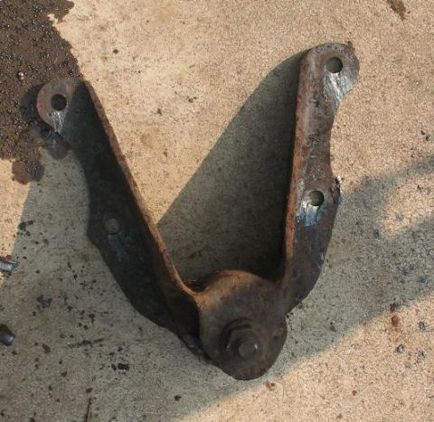 1978 Ford Bronco - A single, heavily rusted metal component, likely a suspension part, lies on a concrete surface.