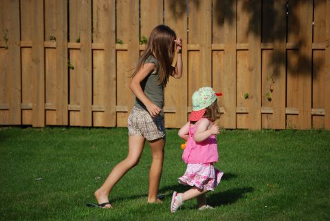 2000 Ford Crown Victoria - Two young girls enjoy a sunny day playing in a backyard, with a wooden fence and green grass providing the backdrop.