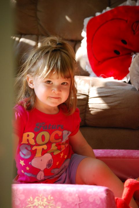 2000 Ford Crown Victoria - A young child wearing a red t-shirt with a cartoon character and text sits on pink furniture.