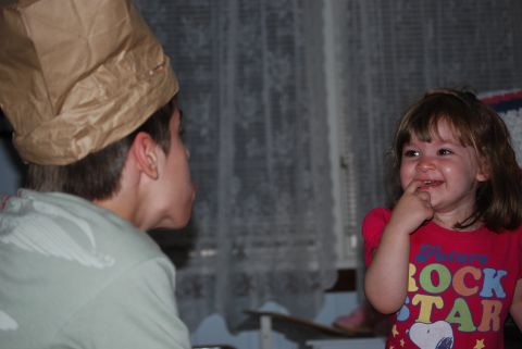2000 Ford Crown Victoria - Two children are playing dress-up indoors, one with a paper bag hat and the other in a colorful shirt.