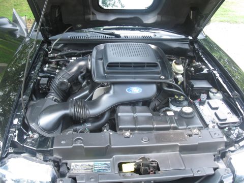 2003 Ford Mustang - The engine bay of a black 2003 Ford Mustang, the prominent Ford logo on the air intake system.
