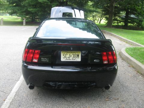 2003 Ford Mustang - Rear view of a black 2003 Ford Mustang Mach 1 with a spoiler and dual exhaust pipes.