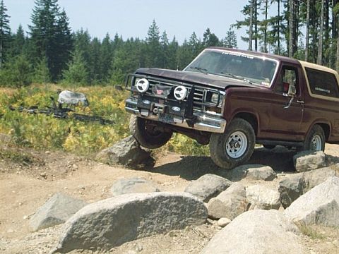 1986 Ford Bronco - This 1986 Ford Bronco is shown tackling a challenging off-road course with large rocks.