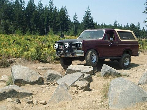 1986 Ford Bronco - Ford Bronco tackles a challenging rocky trail in a wooded area.
