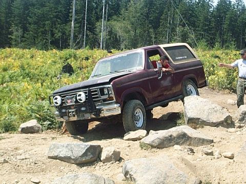 1986 Ford Bronco - This maroon SUV, likely from the early 1980s, is shown tackling a challenging rocky trail.