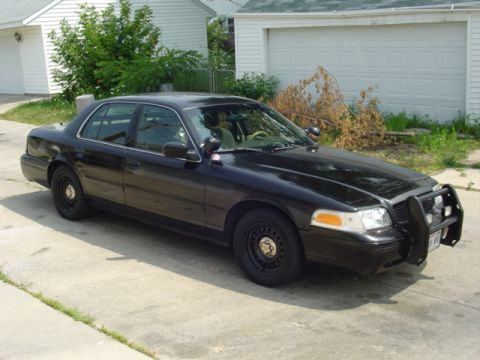 2000 Ford Crown Victoria - This black 2000 Ford Crown Victoria is parked on a concrete driveway in front of a residential garage.