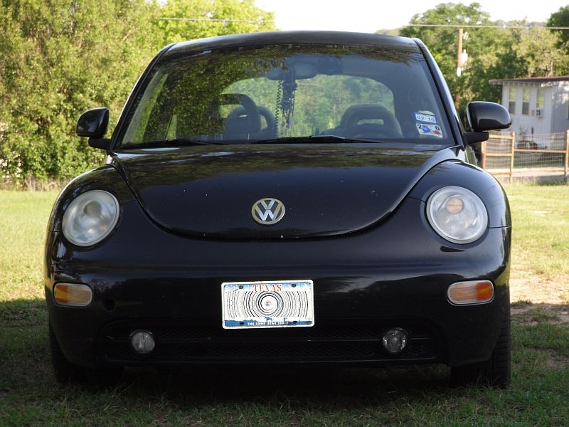 Black Volkswagen Beetle front view, parked on grass with a Texas license plate