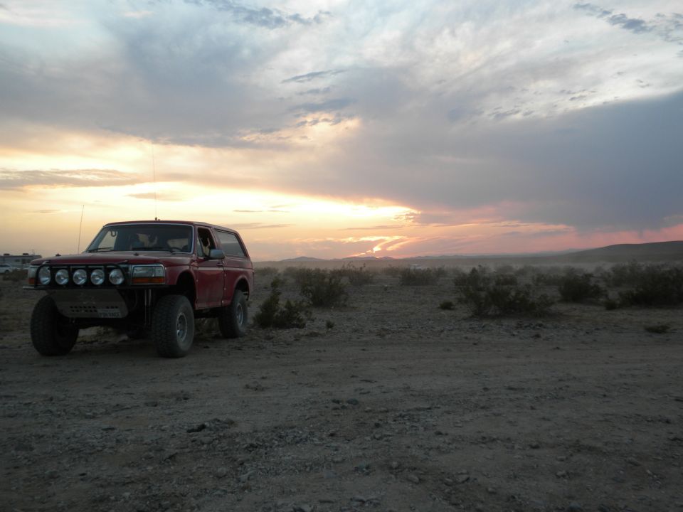 Red SUV with aftermarket bumper and five auxiliary lights parked in a desert