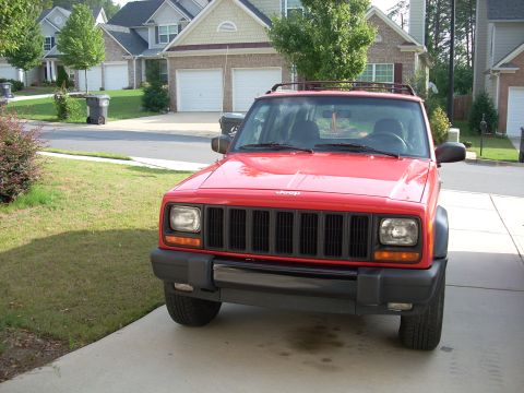 2005 Ford F-250 - A red Jeep Cherokee is parked in a suburban driveway.